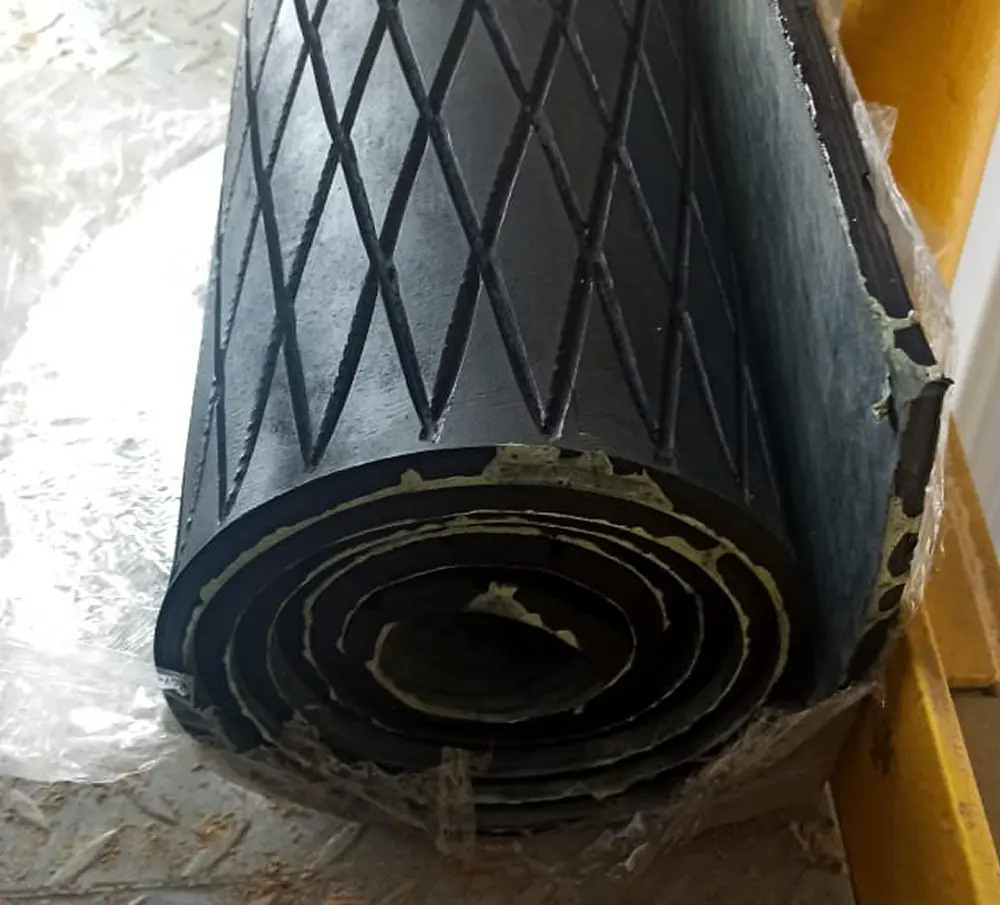 Primer plano de un rollo de material de caucho negro con patrón de rombos.